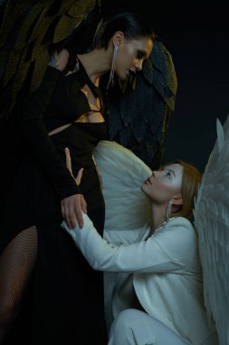 women in Halloween costumes, dark demon tempting holy angel on black backdrop, good vs evil concept clipart