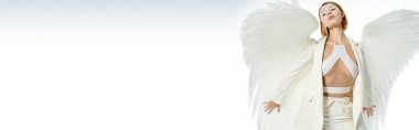 Cadılar bayramı kostümlü güzel melek gibi bir kadın. İlahi kanatlarıyla beyaz pankartta poz veriyor.