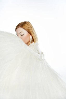 woman with angelic aura obscuring face with divine wings on white backdrop, purity and serene clipart
