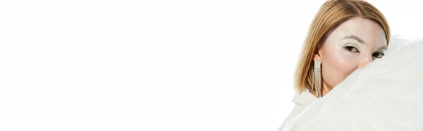 charming angelic woman looking at camera behind ethereal wings on white backdrop, banner