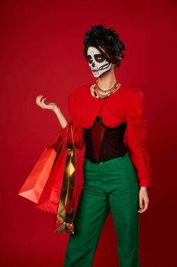 Kafatası makyajlı ve alışveriş torbalı kadın kırmızıya bakıyor, dia de los muertos