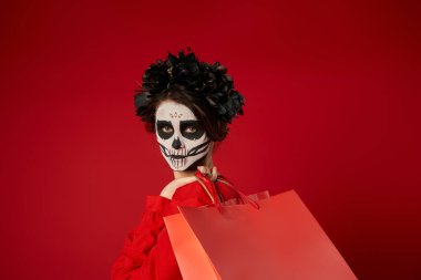 portrait of woman in sugar skull makeup and black wreath with shopping bags on red, seasonal sale clipart