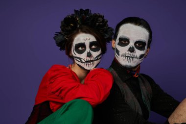 Los Muertos çifti, Catrina makyajlı kadın ve mavi üzerine yaslanan siyah çelenk.