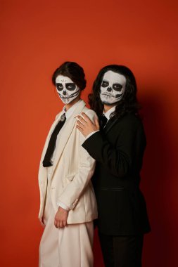 dia de los muertos 'un zarif çifti makyaj ve şık takım elbiseler kırmızı kameraya bakıyor.