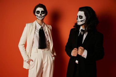 woman in sugar skull makeup and white suit standing with hands in pockets near eerie man on red clipart