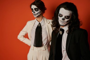 spooky man in catrina makeup looking at camera near woman with hands on waist on red, Day of Dead clipart