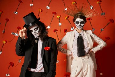Los Muertos Partisi, Catrina makyajlı çift ve kırmızı stüdyoda çiçekli şenlikli kıyafetler.