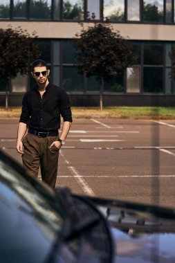 Çekici genç erkek modelin, şık siyah elbisesi içinde arabasına doğru yürürken, seksi sürücüsü...