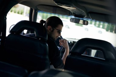 Çekici, at kuyruklu ve direksiyonda güneş gözlüklü, el kaldıran, moda düşkünü seksi bir sürücü.