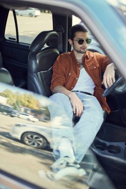Kahverengi gömlekli genç şık erkek model direksiyonun arkasında takılıyor, moda kavramı.