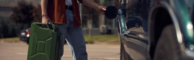 cropped view of young man in brown stylish shirt with jeans refueling his car with petrol, banner clipart