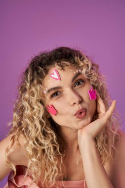 attractive blonde woman with curly hair and bright face stickers expressing astonishment at camera clipart