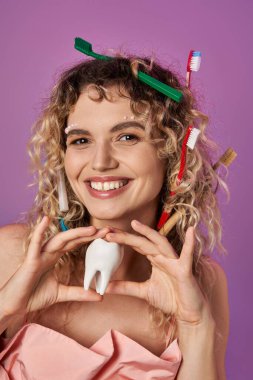 smiley blonde woman with toothbrushes in her curly hair holding tooth, tooth fairy concept clipart