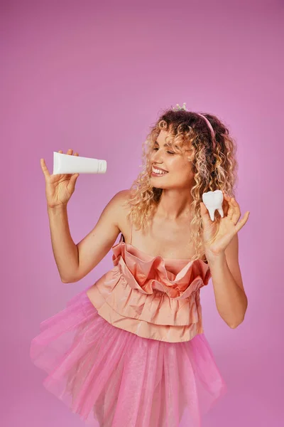 stock image attractive lovely woman in pink fairy attire smiling and holding baby tooth and tooth paste