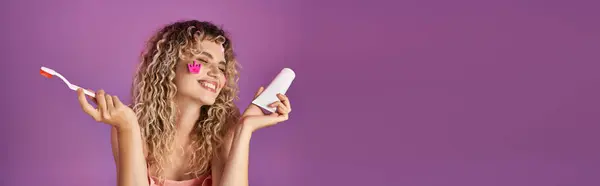 stock image attractive cheerful woman with curly hair and face stickers holding toothbrush and paste, banner