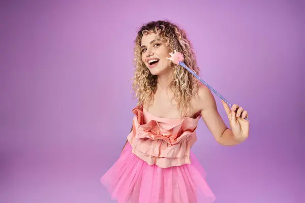 カメラで魔法の杖を保持し 笑顔で活気に満ちたピンクのドレスでスマイリーかわいい歯の妖精 — ストック写真