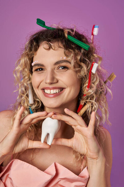 smiley blonde woman with toothbrushes in her curly hair holding tooth, tooth fairy concept