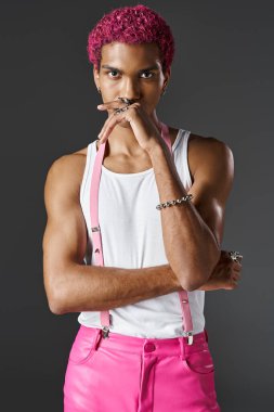 Pembe renkli canlı giyinmiş genç güçlü bir adam. Elinde kamera, moda ve stile bakıyor.