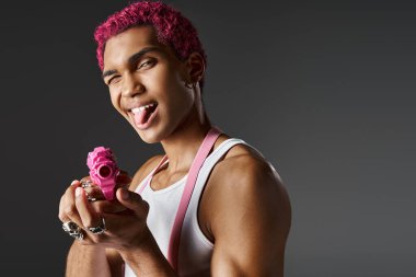 playful pink haired male model sticking out his tongue and leveling his pink toy gun at camera clipart