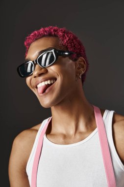 Vogue güneş gözlüklü, pembe saçlı, moda anlayışı olan oyuncu bir adam.