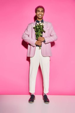handsome man with curly hair posing unnaturally and smiling with rose bouquet in front of him clipart