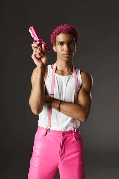 stock image handsome african american man with pink pants and suspenders pointing up toy gun looking at camera