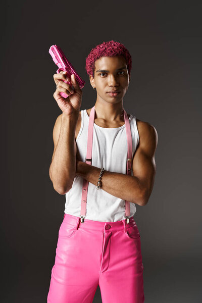 handsome african american man with pink pants and suspenders pointing up toy gun looking at camera