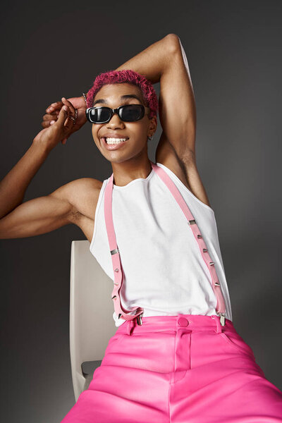 playful young man with pink hair and suspenders smiling wearing sunglasses, fashion concept