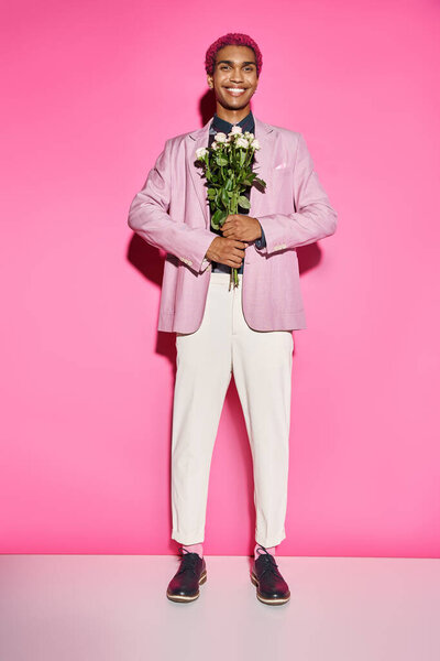 handsome man with curly hair posing unnaturally and smiling with rose bouquet in front of him