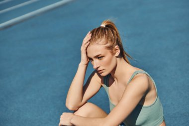 Spor kıyafetleri içinde genç ve güzel bir bayan antrenmandan sonra dinlenirken, kentsel fitness