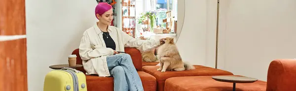 时尚女性与智能手机拥抱波美拉尼亚斯皮茨附近的旅行袋在宠物酒店的休息室 — 图库照片