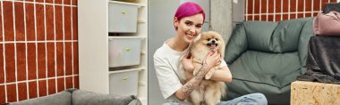 Neşeli köpek bakıcısı Pomeranian Spitz 'e sarılıyor ve evcil hayvan otelinde kameraya bakıyor, sevgi dolu bakım, afiş