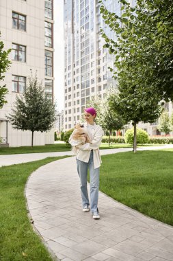 Pomeranian Spitz 'i olan neşeli bir kadın şehirde, sokak manzarasında yürüyor.