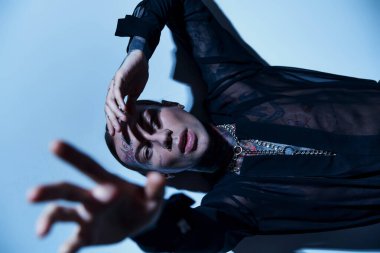 Elleri kameranın önünde olan dövmeleri ve aksesuarları olan seksi genç erkek manken, moda anlayışı.