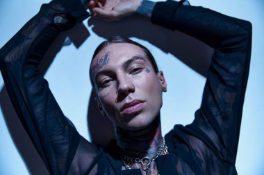 İyi görünümlü, şeffaf gömlekli, elleri havada, kameraya bakan genç bir adam, moda konsepti.