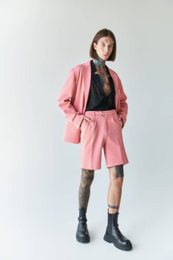 Pembe ceketli ve şortlu yakışıklı genç adam elleri ceplerinde poz veriyor kameraya bakıyor, moda