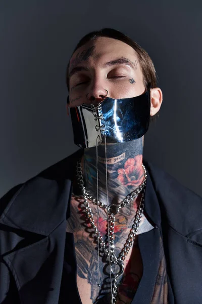 portrait of alluring man in black futuristic mask posing with closed eyes, fashion concept