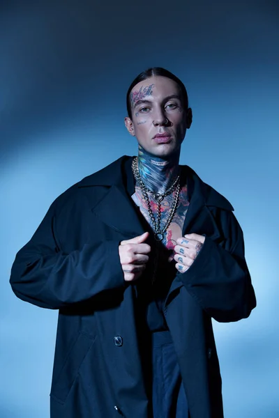 stock image good looking stylish male model with tattoos posing with hands on his black coat, fashion concept