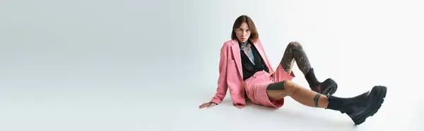 stock image sexy man in pink blazer and shorts sitting on floor and looking at camera, fashion concept, banner