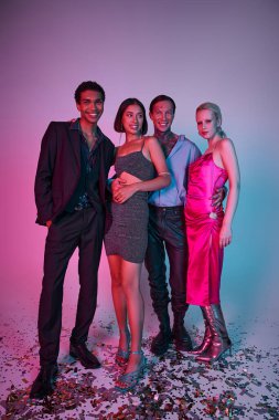 Şenlikli giyinmiş neşeli çoklu etnik erkekler ve mor pembeyle Noel 'i kutlayan kadınlar.