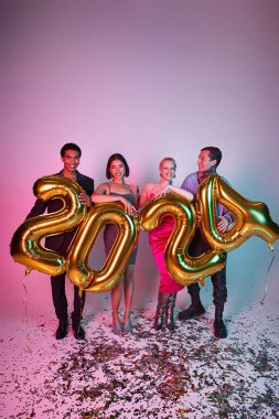 Yeni yıl konsepti, mutlu çoklu etnik arkadaşlar üzerinde 2024 numara olan mor pembe balonlar tutuyorlar.