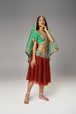 Ulusal giysili neşeli genç Hintli kadının dikey çekimi ve çene altında elle poz veren bindi nokta