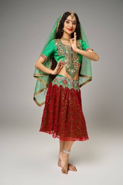 Geleneksel choli ve etek giymiş neşeli, güzel Hintli kadın jest yapıyor ve kameraya bakıyor.