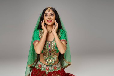 Ulusal kostümlü neşeli Hintli kadın. Elleri yüzlerine yakın poz veriyor.