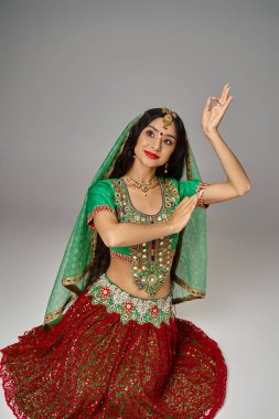 Çekici Hintli kadın modeli alnında bindi noktasıyla yerde duruyor ve elleriyle işaret ediyor.