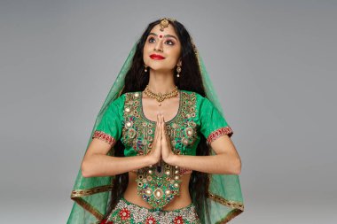 Ulusal kostümlü güzel Hintli kadın bindi noktasıyla ve aksesuarlarıyla dua ediyor ve başka tarafa bakıyor.