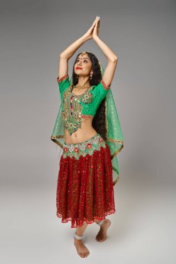 Geleneksel kostümlü Hintli güzel bir kadının kollarını kaldırarak dans ettiği dikey çekim.