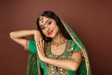 Ulusal arenada bindi noktasıyla güzel bir Hintli kadın kameraya gülümsüyor ve el kol hareketi yapıyor.