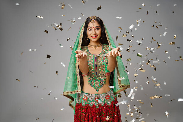 beautiful indian woman in national clothes with bindi showing open palms and smiling at camera