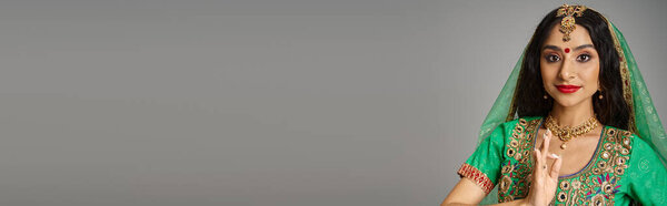 young indian woman in traditional clothes with bindi dot gesturing and looking at camera, banner